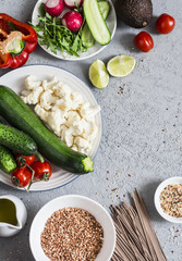 Vegetarian food. Zucchini, cauliflower, sweet pepper, soba noodles, buckwheat, avocado, tomatoes  - healthy vegetarian food. On a gray background, top view