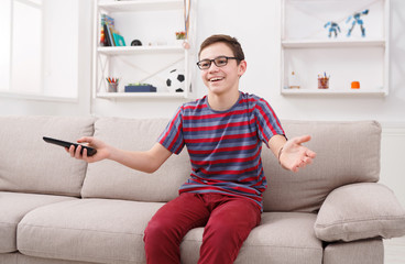 Cheerful boy watching funny TV show at home