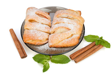  Buns with apple, cinnamon and mint sprinkled with powdered sugar on a plate.