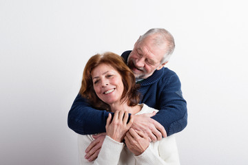 Beautiful senior couple in love hugging. Studio shot.