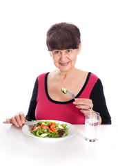 Pension age good looking smiling woman eating green salad