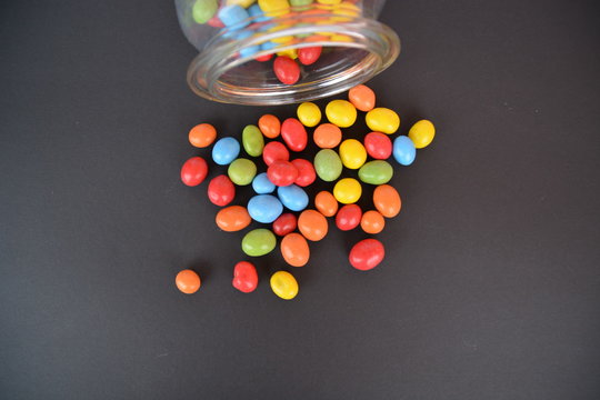 chocolate lentils in a jar on a black ground with colored background - Powered by Adobe