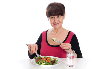 Obraz na płótnie Canvas Pension age good looking smiling woman eating green salad