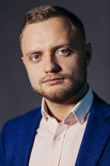 Portrait of serious fashionable handsome man in blue suit looking at camera