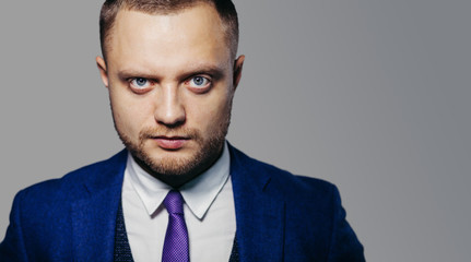 Portrait of serious fashionable handsome man in blue suit looking at camera
