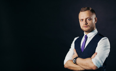 Handsome man with arms folded standing over black background and looking at camera
