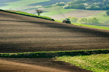 Farmer in tractor preparing land with seedbed cultivator, spirng, countryside in Ponidzie, Poland