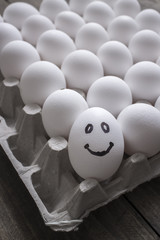 White and one smile eggs  in a cardboard box.