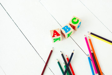 wooden english abc cubes and colorful pencils on the white neutral background.