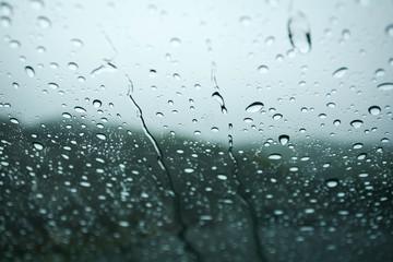 Rain drops on window glasses surface with cloudy background .