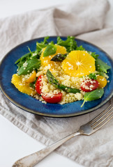 Couscous salad With orange, spinach leaves, asparagus, cherry tomatoes and basil in a blue rustic dish with copy space. Vegetarian food Concept 