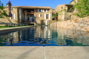 The edge of a residential swimming pool in a garden in the Ardeche, France. With blurred background.