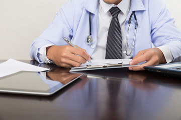 doctor writing RX prescription in medical office clinic on desk, stethoscope with clipboard