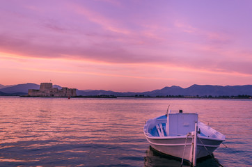 traditional wooden fishing boat in foreground and the Venetian castle of Bourtzi in background.