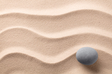 Fototapeta na wymiar round stone on beach sand. Zen meditation rock.