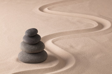 Fototapeta na wymiar balancing black rocks in zen sand garden. Stone pile stacked in balance. Spa wellness or yoga background...