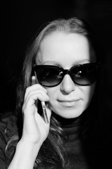 Portrait of a young woman in sunglasses with a phone