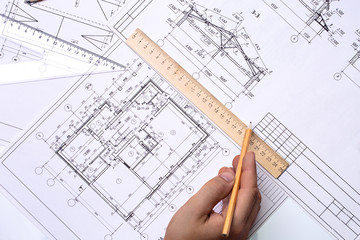 Man architect draws a plan, schedule, design, geometric shapes with a pencil and a wooden ruler. The figure is close to the transparent line of triangle