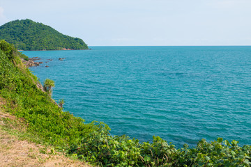 Naklejka premium View from the mountain peak along blue sea and high rocks against sky. Colorful mountain landscape. Vacation on seashore. Summer travel in Thailand.