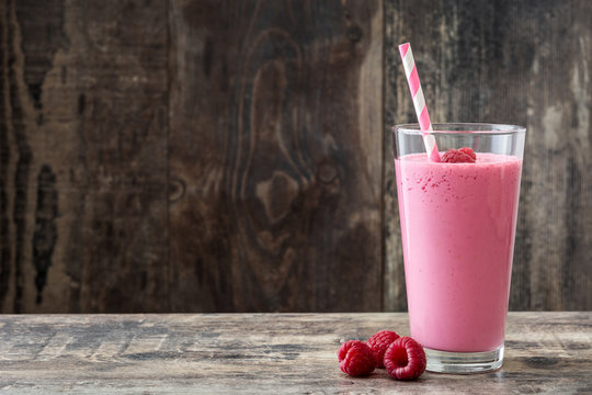 Raspberry smoothie in glass on wooden table. Copyspace
