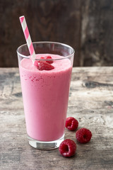 Raspberry smoothie in glass on wooden table

