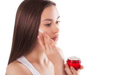 Pretty woman with perfect skin holding a tube with face cream. Young girl with hands on the front. Red jar of cream. Close-up. Isolated background. Beautiful woman wearing a face and hands cream.