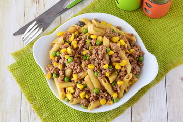 Pasta with minced meat, green peas and yellow corn in a white plate. Home cooking. Healthy eating concept