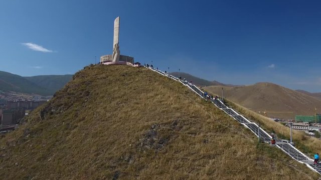 Zaisan Memorial monument USSR soldier with flag. Capital of Mongolia Ulaanbaatar observation deck. Tourist walk uphill mountains. Aerial Drone flight accent forward move 4k footage.
