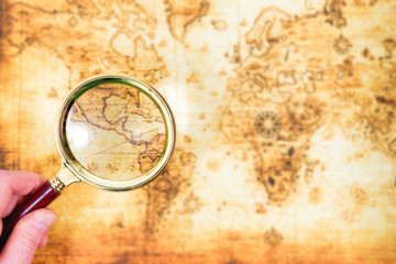 Fototapeta na wymiar Old map and magnifying glass in a hand