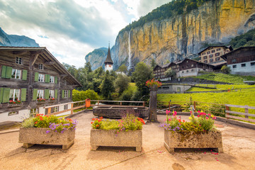 The picturesque landscape with flowers, a waterfall and canyon church in Lauterbrunnen in the Swiss Alps, Switzerland, Europe