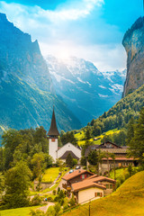 The picturesque landscape with flowers, a waterfall and canyon church in Lauterbrunnen in the Swiss Alps, Switzerland, Europe