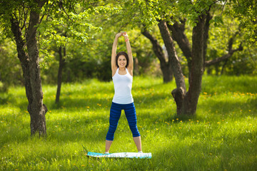 Young girl working out outdoors. Beautiful woman doing pilates, yoga and fitness exercices on nature.