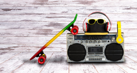 The concept of the music Hip hop style.Vintage audio player with headphones.Skateboard ,fashionable cap and sunglasses.isolated