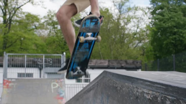 Young skateboarder jumps onto a wall and grinds, in slow motion