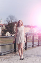Pretty girl in fashionable grey dress walking on pavement