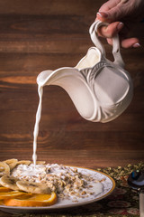 Milk pours into the oatmeal on a wooden background