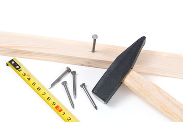 Hammer, construction tape measure and nails on a white backgroun