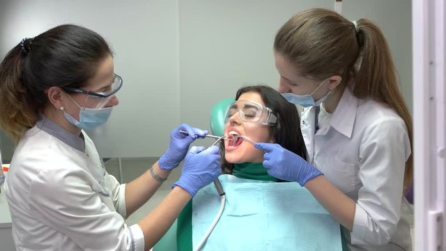 Two dental doctors and patient. Procedure at the dentist office.