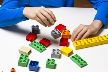 Child holds building blocks in his hands and play in kindergarten or at home