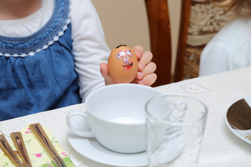 Dziewczynka trzyma w dłoni kolorowe jajko Wielkanocne.
