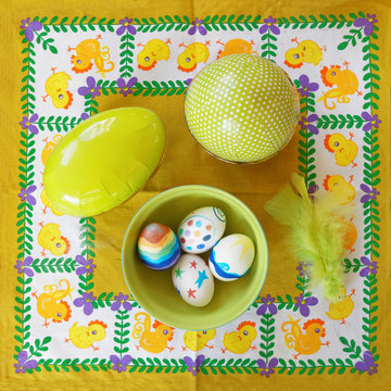 Painted Eastern egg on a yellow tablecloth with chickens