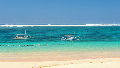 Fototapeta na wymiar beach in Bali with sea views and two small boats with the coast line on a Sunny day with small clouds on the horizon the horizontal position