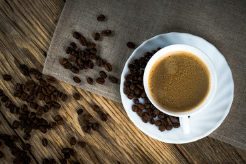 Coffee cup and beans on a wooden table.