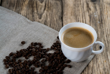 Coffee cup and beans on a wooden table.