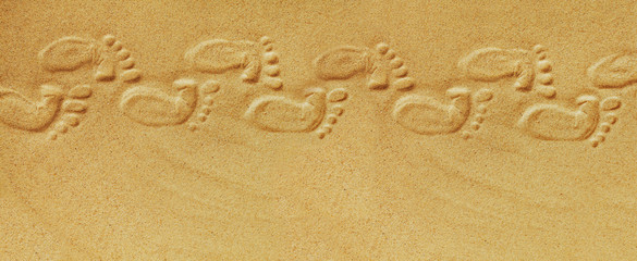 Cute baby footsteps on sandy beach with space for text or desighn