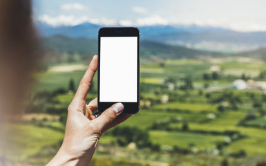 Hipster photograph on smart phone gadget mobile, mock up of blank screen. Traveler hold and using in hand mobile on background mountain landscape horizon. Tourist look map on trip, lifestyle concept