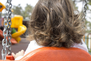child on swing from back in park