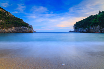 Obraz premium Long exposure landscape of Paleokastritsa famous sand beach in close bay on Corfu island at dusk, Ionian archipelago, Greece.