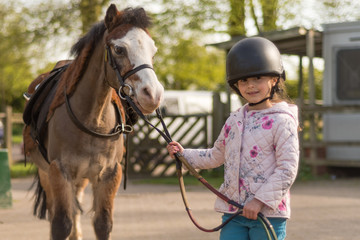 Young girl wearing riding helmet leading Welsh pony. Young girl wearing riding helmet leading Welsh pony