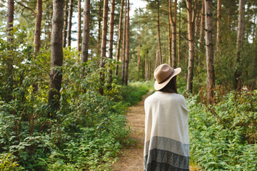 A girl in a poncho and a hat in forest